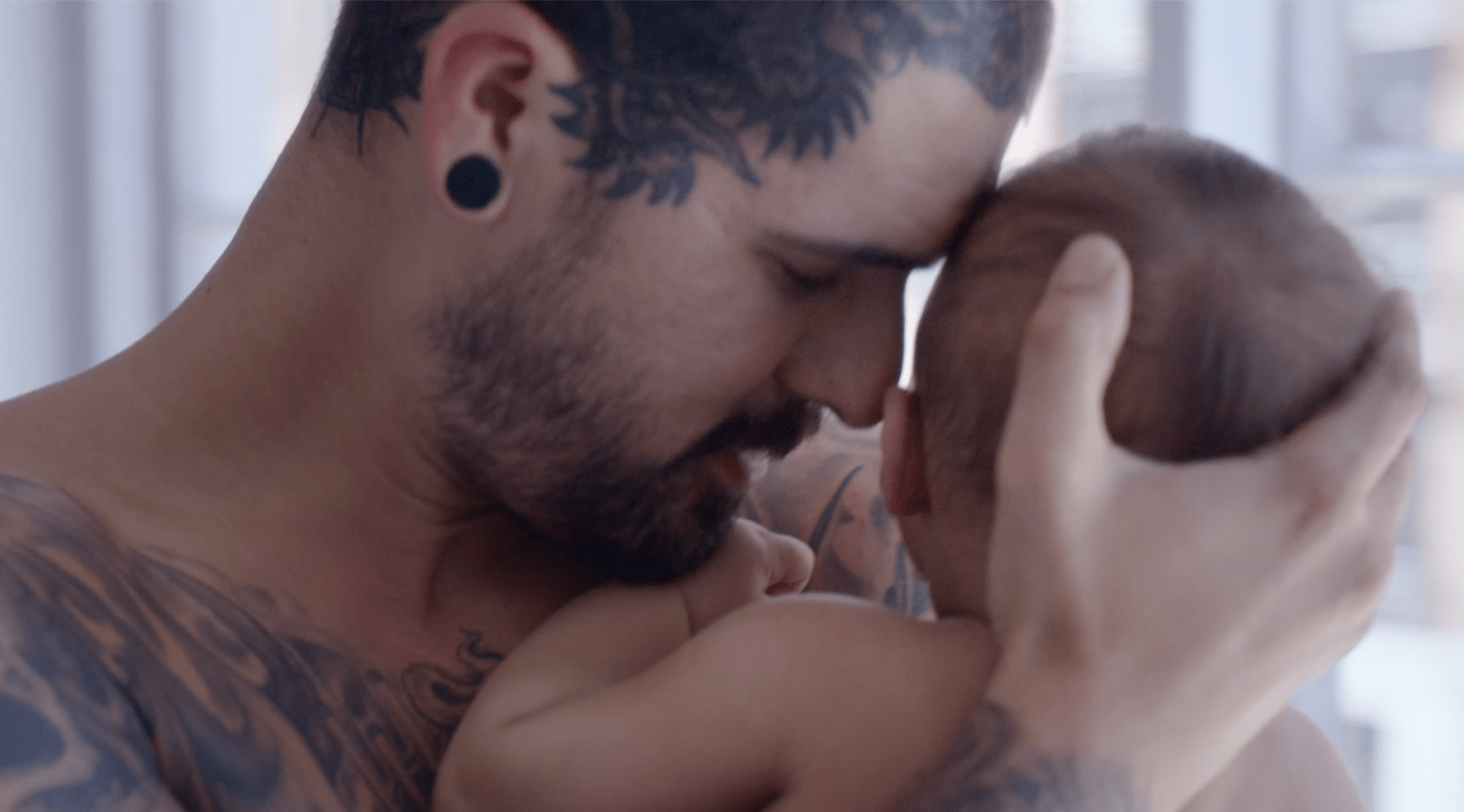 homem com tatuagens com bebé ao colo